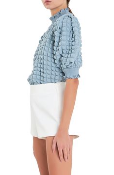 Elbow-length puff sleeves frame this bubble-textured top designed with sweet smocked accents. Mock neck Elbow-length sleeves with smocked cuffs 95% polyester, 5% spandex with 100% polyester contrast Hand wash, dry flat Imported Trendy Textured Knit Top With Puff Sleeves, Textured Puff Sleeve Tops For Summer, Fall Smocked Puff Sleeve Top With Ruffles, Blue Puff Sleeve Top With Gathered Sleeves, Fall Puff Sleeve Smocked Top With Ruffles, Fall Smocked Top With Ruffles And Puff Sleeves, Textured Puff Sleeve Summer Tops, Trendy Puff Sleeve Top With Ruffles And Balloon Sleeves, Summer Textured Puff Sleeve Tops