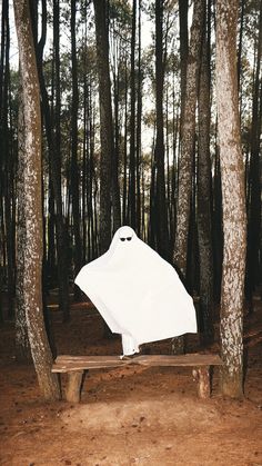 a white umbrella sitting on top of a wooden bench in the middle of a forest