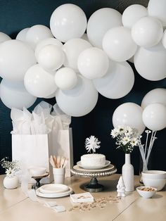 a table topped with lots of white balloons next to plates and vases filled with flowers