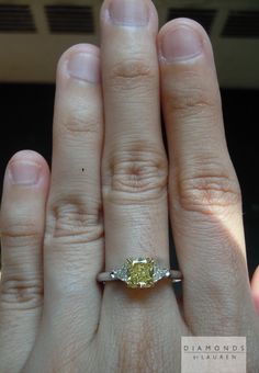 a woman's hand with a yellow diamond ring on it