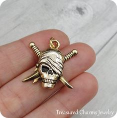 This Pirate Skull Charm comes with a gold jump-ring as pictured. Please note that photo is not to scale and may appear larger to show detail. Refer to exact measurements below.Additional attachments (lobster clasp, large-hole bead, necklace chains) are available from the charm-attachments drop-down menu.  For a visual example of the different attachments and what each one is best suited for, scroll through the photos until you see the example photo or visit https://etsy.me/2BY7DAW for detailed i Novelty Gold Metal Jewelry, Gold Skull-shaped Engraved Jewelry, Gold Skull Collectible Jewelry, Gold Skull Jewelry Collectible, Gold Skull Jewelry For Collectors, Handmade Gold Novelty Jewelry, Adjustable Gold Skull Bracelets, Gold Adjustable Skull Bracelets, Pirate Gifts