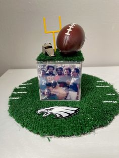 a football sitting on top of a green field next to a plastic container filled with photos