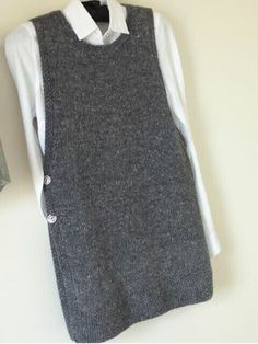 a gray sweater vest hanging on a white wall