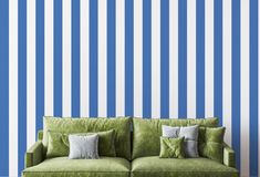 a green couch sitting in front of a blue and white striped wall