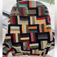 a chair covered in a multicolored patchwork blanket sitting on top of a table