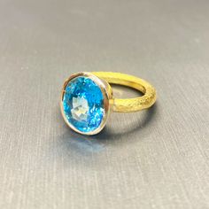 One-of-a-kind, hand-crafted ring centering 10.20 carat oval shape, fine gem quality vivid color Blue Zircon set in 18karat yellow gold bezel and 22karat yellow gold hammered setting. Size 7, can be sized upon request. Zircon might be one of the most under-appreciated colored gemstones and please do not confuse it with cubic zirconia, or CZ, an artificial product from the mid-1970s. Zircon found in Australia is the oldest mineral on earth: 4.4 billion years old. In the Middle Ages, this gem was t Gold Oval Topaz Ring With Bezel Setting, Oval Yellow Gold Topaz Ring With Bezel Setting, Handmade Gold Topaz Ring With Oval Shape, Handmade Gold Topaz Ring In Oval Shape, 3d Printed Necklace, 3d Printed Earrings, Colored Gemstones, The Middle Ages, Mesh Bracelet