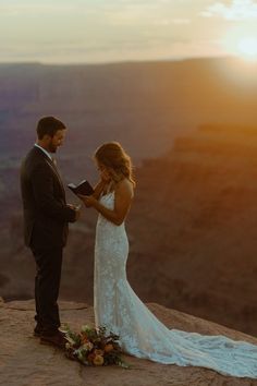 a bride and groom standing at the top of a cliff during their sunset wedding ceremony