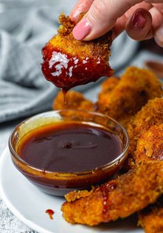 a person dipping sauce onto some fried food