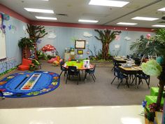 a classroom with lots of desks, chairs and plants on the wall in front of it