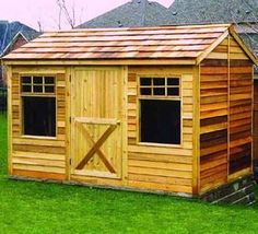 a wooden shed sitting on top of a lush green field