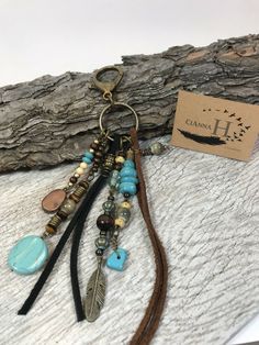 a keychain with charms and beads on top of a piece of driftwood