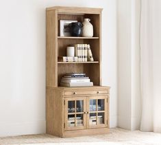 a wooden bookcase with glass doors on the front and bottom, in an empty room