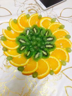 an arrangement of sliced oranges and kiwi on a table with a cell phone in the background