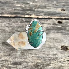 "This handmade sterling silver ring features a natural, high grade Turquoise Mountain stone in a smooth bezel with prong details, along a wide, comfortable band. The stone is a beautiful, green color, mined here in the USA. The setting is entirely handmade, crafted of fine silver (.999) and sterling silver (.925) and has been oxidized to highlight the fine details and then polished to a high shine. Face of ring measures 1 1/4\"tall x 5/8\" wide. Ring is a US size 7.5 and cannot be resized. Pleas Artisan Turquoise Chrysoprase Rings, Adjustable Chrysocolla Turquoise Ring, Silver Turquoise Ring With Cabochon Chrysoprase, Turquoise Chrysocolla Ring With Large Stone, Oval Turquoise Chrysoprase Ring, Large Stone Turquoise Ring In Chrysocolla, Turquoise Chrysoprase Ring, Untreated Chrysocolla Turquoise Ring In Silver, Oval Turquoise Chrysocolla Ring In Silver