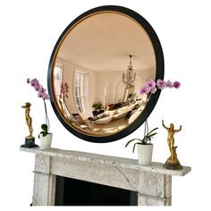 a living room with a fire place and mirror on the fireplace mantel, decorated with pink flowers