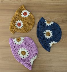 three crocheted hats sitting on top of a wooden floor