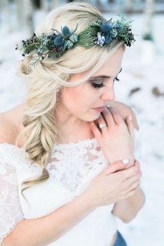 a woman wearing a wedding dress and holding her hand to her chest in the snow