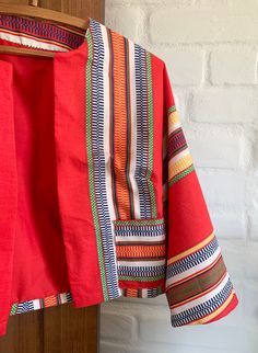 This colorful jacket is lightweight and perfect for a summer evening. Bright colors of red, yellow, and blue make up this vintage fabric. With 3/5 legnth sleeves, front pockets, and is lined in matching red. No closure, meant to be worn open. Would look great with high waisted jeans or a shirt. Multicolor Summer Outerwear With Pockets, Fitted Orange Outerwear For Summer, Multicolor Cotton Outerwear For Summer, Retro Multicolor Summer Outerwear, Bohemian Summer Outerwear With 3/4 Sleeves, Bohemian Outerwear With 3/4 Sleeves For Summer, Summer Cotton Outerwear With 3/4 Sleeve, Bohemian Orange Outerwear For Summer, Summer Bohemian Orange Outerwear