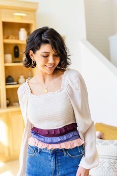 a woman standing in front of a book shelf wearing a white top and blue jeans