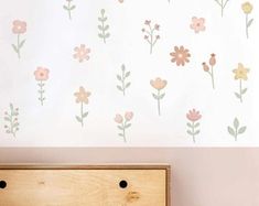 a wooden dresser sitting next to a wall with flowers painted on the walls and below it