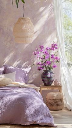 a bed with purple sheets and pillows in a bedroom next to a plant on the wall