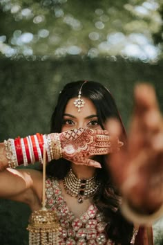 a woman holding her hands up to her face with henna and bracelets on