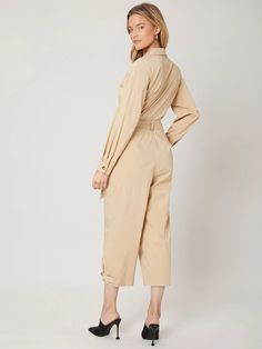 The Long Sleeve Belted Utility Jumpsuit is a stylish and practical piece of clothing suitable for various occasions. It features a plain design with a collar neckline, long sleeves, and regular sleeves. The jumpsuit has a high waistline and comes with a belt that cinches at the waist to create a flattering silhouette. The slight stretch in the fabric provides comfort and ease of movement. It is available in capris length, making it a perfect choice for both casual and formal events. Specificatio Long Sleeve Jumpsuits And Rompers For Office, Fall Workwear Solid Color Jumpsuits And Rompers, Fall Workwear Jumpsuits And Rompers In Solid Color, High Waist Belted Jumpsuits For Workwear, Fall Season Belted Overall Jumpsuits And Rompers, Belted Long Sleeve Jumpsuits For Work, Belted Long Sleeve Jumpsuits For Spring, Casual Long Sleeve Belted Jumpsuits And Rompers, Solid Color Long Sleeve Jumpsuit With Tie Waist