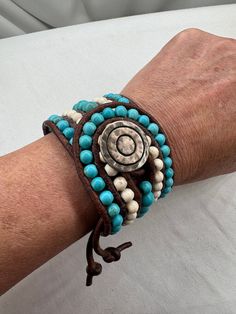 Turquoise and white beads are hand woven onto genuine, natural dye brown leather 3mm cord. Closure is a metal alloy button with circular design. Boho cowgirl handmade cuff statement bracelet. The bracelet in the photos is the bracelet you will receive - it is not made to order, however I welcome custom requests! Size: 1 3/4" wide 8" end to end 6" to 7" wrist If you would like a custom bracelet in this design, please message me and I will work with you to create the perfect bracelet for you. My P Adjustable Turquoise Leather Bracelet In Rustic Style, Adjustable Rustic Turquoise Leather Bracelet, Adjustable Turquoise Leather Bohemian Bracelet, Handmade Turquoise Leather Bracelet, Bohemian Style, Handmade Turquoise Leather Bracelet In Bohemian Style, Bohemian Turquoise Leather Bracelet With Round Beads, Handmade Bohemian Turquoise Leather Bracelet, Handmade Adjustable Turquoise Leather Bracelet, Handmade Southwestern Turquoise Leather Bracelet