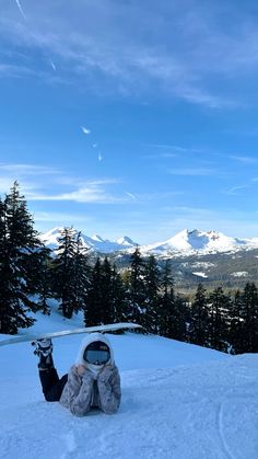 a person laying in the snow with skis on their feet and mountains in the background