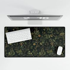 a computer mouse and keyboard sitting on top of a black floral print desk mat that says 2010