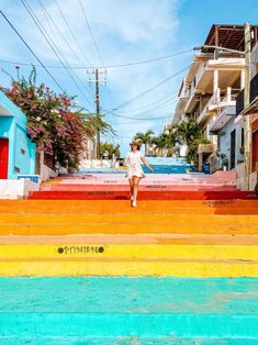 a woman standing on the top of some steps in front of buildings with colorful stairs