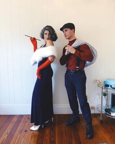 a man and woman standing next to each other in front of a wall wearing costumes