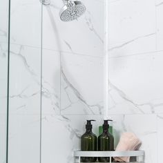 a bathroom with marble walls and flooring, two soap dispensers on the shelf