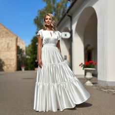 a woman in a white dress is standing outside