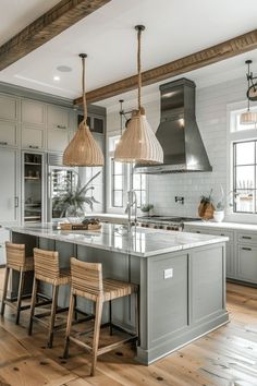 a large kitchen with wooden floors and gray cabinets, two pendant lights over the island