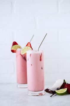 two drinks with strawberries and lime on the side