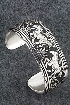 This expertly crafted sterling silver bracelet featuring horses was made by Navajo silversmith Richard Singer. The back is signed R Singer and stamped .925.Size: 5 5/8" (will fit up to a 6 3/4" wrist)Gap: 1 1/8"Width: 1"Free shipping on all orders! We ship with USPS and always include tracking. All orders ship within a day of payment.Returns are accepted up to 30 days after you receive your order. Just send us a message. Our shop offers cash back or store credit. The item must be returned in new Western Sterling Silver Cuff Bracelet, Western Sterling Silver Bracelets, Western Sterling Silver Adjustable Bracelet Stamped 925, Silver Bracelet With Inlay For Collectors, Western Style Sterling Silver Cuff Bracelet, Western Style Sterling Silver Bracelets, Western Style Engraved Sterling Silver Jewelry, Adjustable Sterling Silver Western Bracelet, Handcrafted Silver Bracelets As Gift