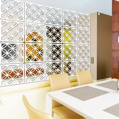 a dining room table with chairs and a wall made out of decorative tiles behind it