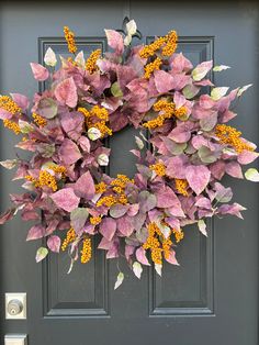 a wreath with yellow and purple flowers is hanging on the front door's black door