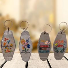 four key chains with different designs on them sitting on a wooden table in front of a blurry background