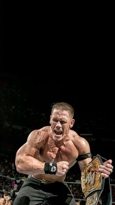 a man holding a wrestling belt in front of a crowd at a sporting event, with his mouth wide open