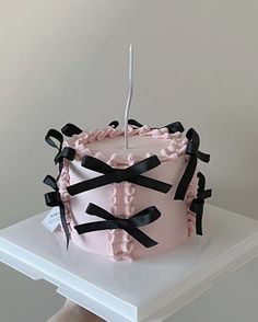 a pink cake with black ribbons on it