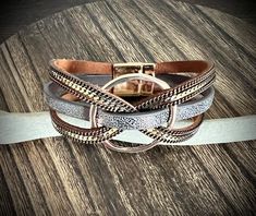 three different colored leather bracelets sitting on top of a wooden table