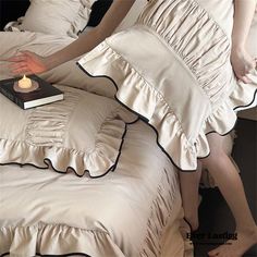 a woman laying in bed next to a stack of pillows with a book on it