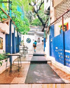 a woman is walking down the stairs in an alleyway with tables and chairs on either side