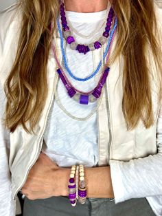 a close up of a person wearing a necklace with beads on it and two bracelets hanging from the neck