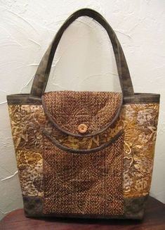 a brown and tan purse sitting on top of a wooden table next to a white wall