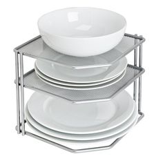 a stack of white plates and bowls sitting on top of each other in front of a metal rack