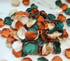 several different colored flowers on a white table with green and orange petals scattered around them