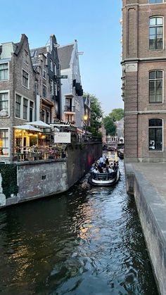 a boat traveling down a river next to tall buildings on either side of the street